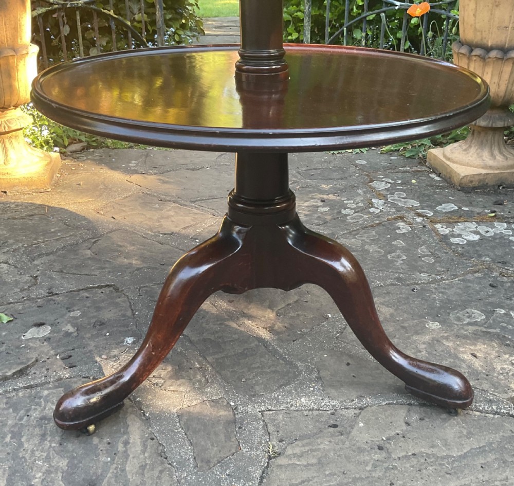 A George III mahogany three-tier dumb waiter featuring graduated circular trays supported on a central turned column and tripod base with castors. View II