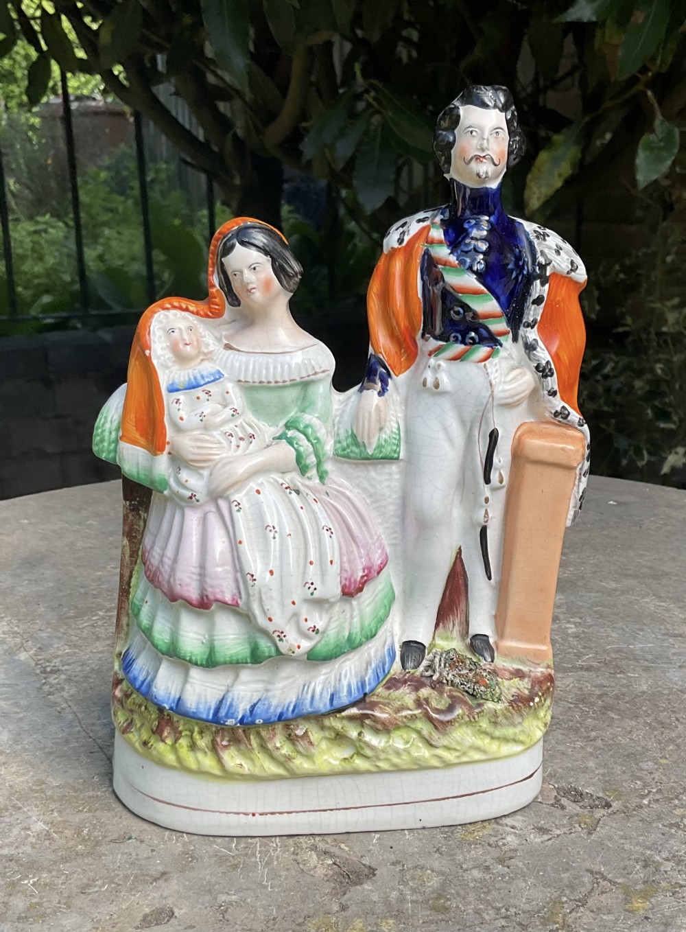 A Victorian Staffordshire earthenware flatback figure depicting Emperor Napoleon III standing beside Empress Eugenie holding an infant, finished in polychrome glazes.
