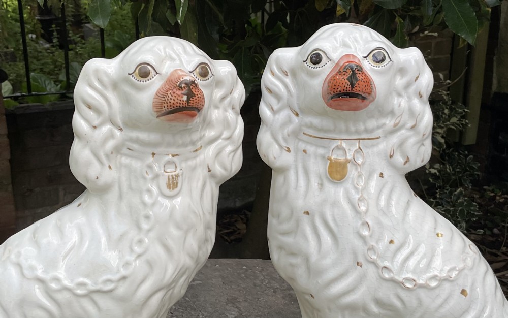 A pair of seated Victorian white earthenware Staffordshire spaniel figurines decorated with gilded chains and painted muzzles. View II