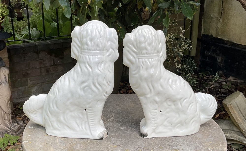 A pair of seated Victorian white earthenware Staffordshire spaniel figurines decorated with gilded chains and painted muzzles. View V