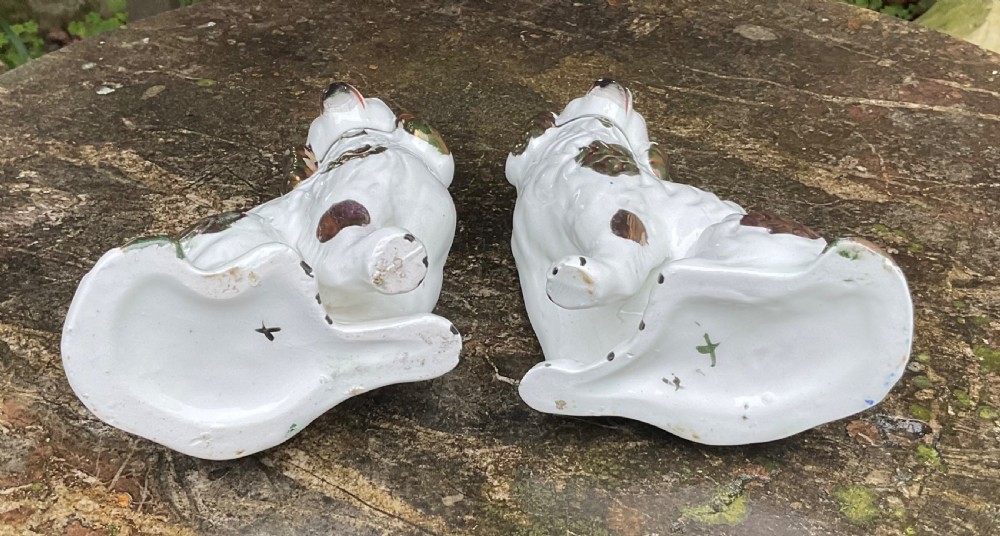 A pair of seated white Victorian ceramic Staffordshire spaniel dog figurines featuring copper lustre patches and ears. View V
