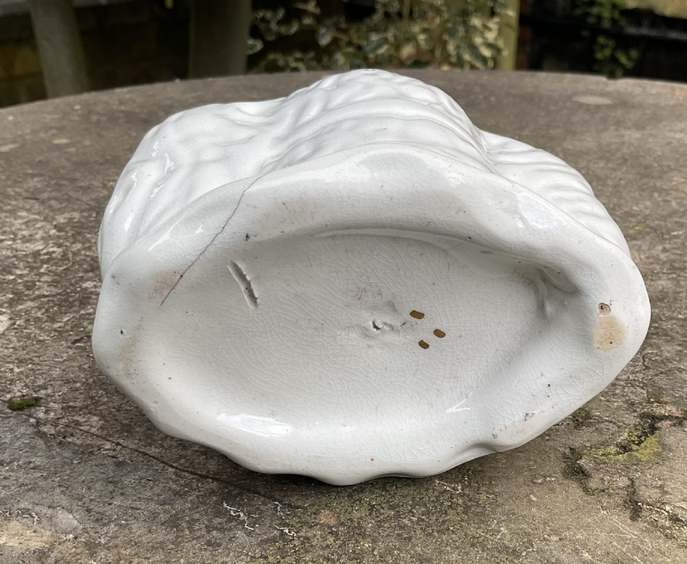 A Victorian off-white ceramic Staffordshire spaniel head money box featuring hand-painted yellow eyes, a black muzzle, and subtle gilt accents. View VI