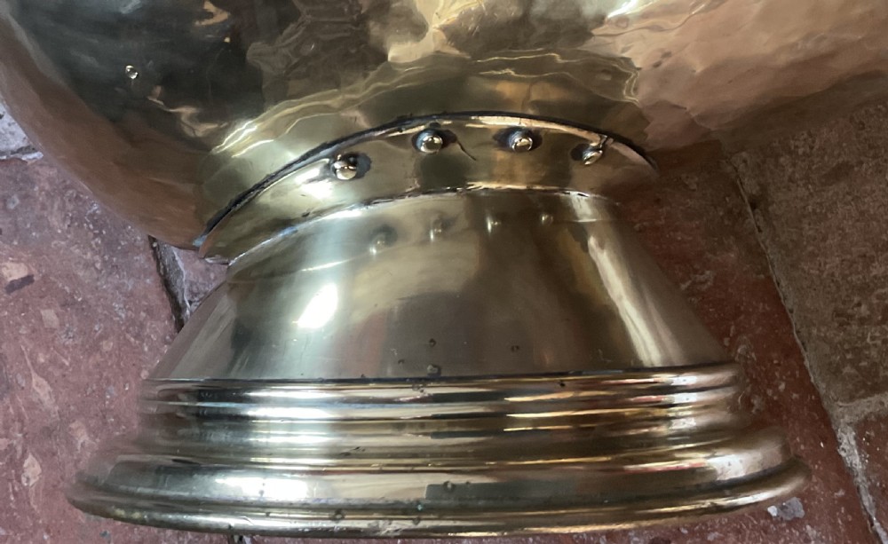 A Victorian brass coal helmet scuttle resting on a pedestal base, complete with an ebonised wooden handle and a matching brass scoop. View VII
