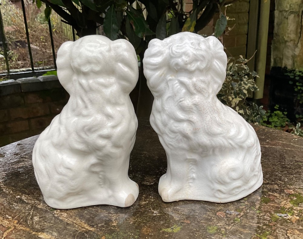 A pair of Victorian white ceramic Staffordshire spaniel figurines decorated with gilt accents and black painted muzzles. View III