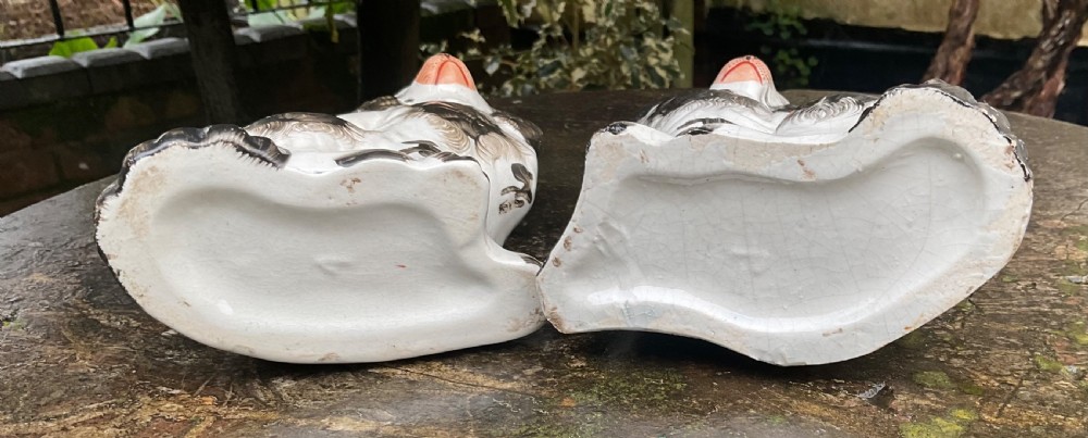A pair of Victorian black and white glazed earthenware Staffordshire spaniel dog figurines sitting facing inward. View V