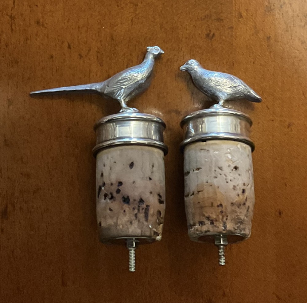 A pair of mid-twentieth-century Asprey silver bottle stoppers featuring cast pheasant finials above natural cork bodies.