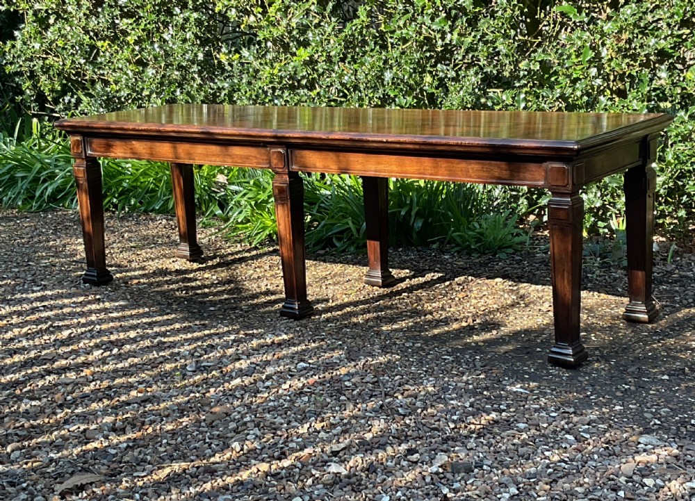 An Edwardian long polished mahogany window seat featuring a rectangular top and six tapered square legs with block details.
