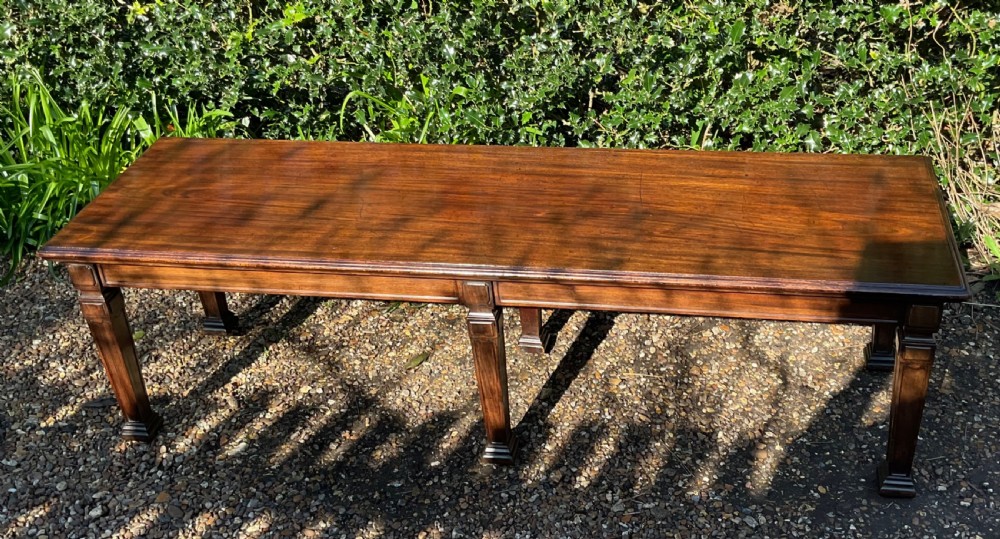 An Edwardian long polished mahogany window seat featuring a rectangular top and six tapered square legs with block details. View V