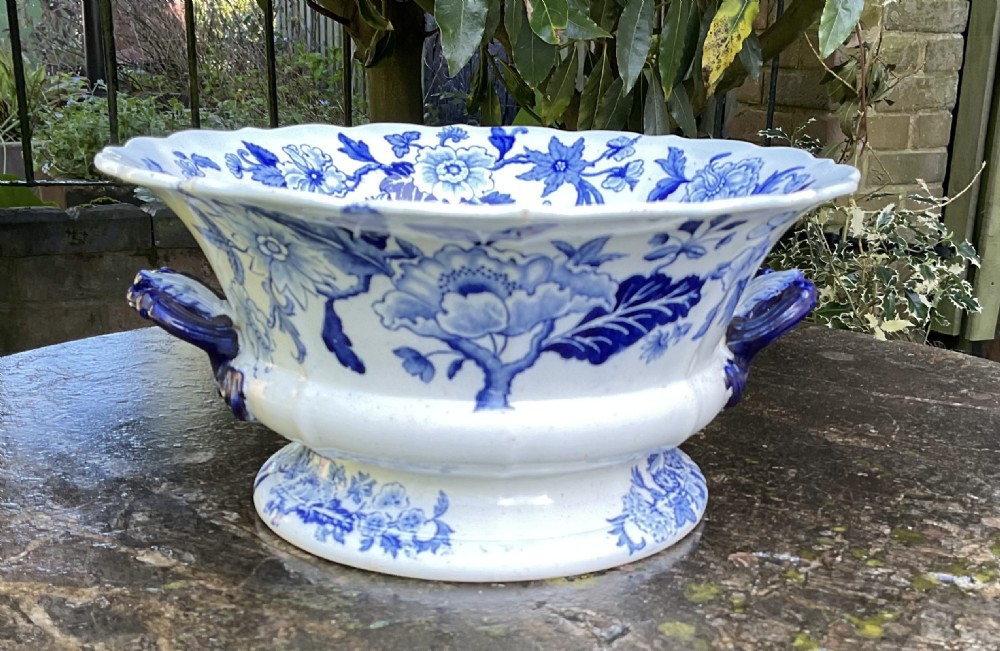 A Georgian blue and white transferware ceramic bowl with twin side handles, a floral pattern, and a raised pedestal foot.