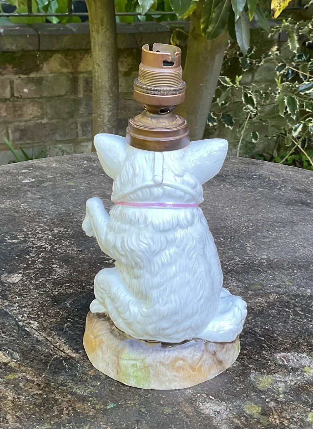 A late 19th-century German white glazed porcelain lamp base sculpted as a seated Spitz dog with orange glass eyes and a brass bulb fitment atop its head. View III