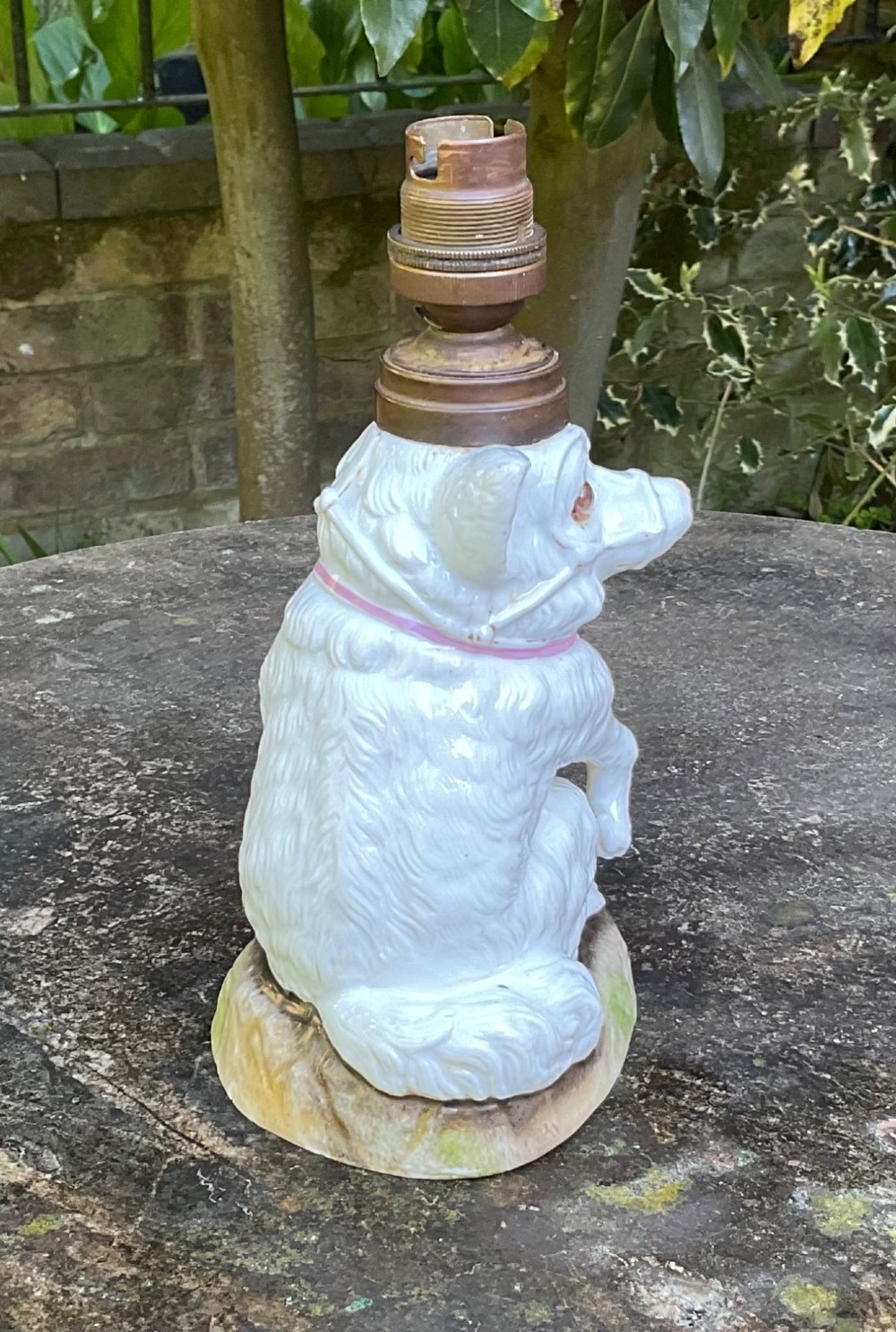 A late 19th-century German white glazed porcelain lamp base sculpted as a seated Spitz dog with orange glass eyes and a brass bulb fitment atop its head. View IV