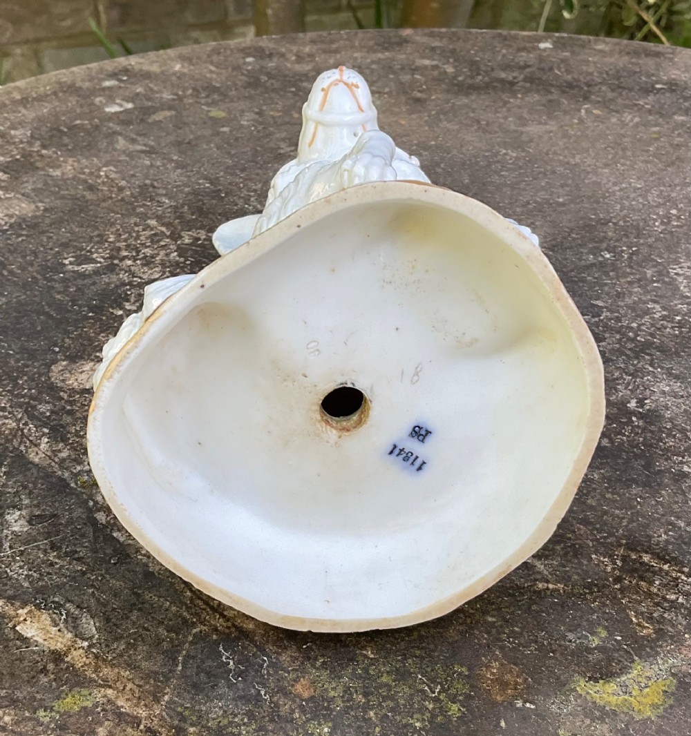 A late 19th-century German white glazed porcelain lamp base sculpted as a seated Spitz dog with orange glass eyes and a brass bulb fitment atop its head. View V