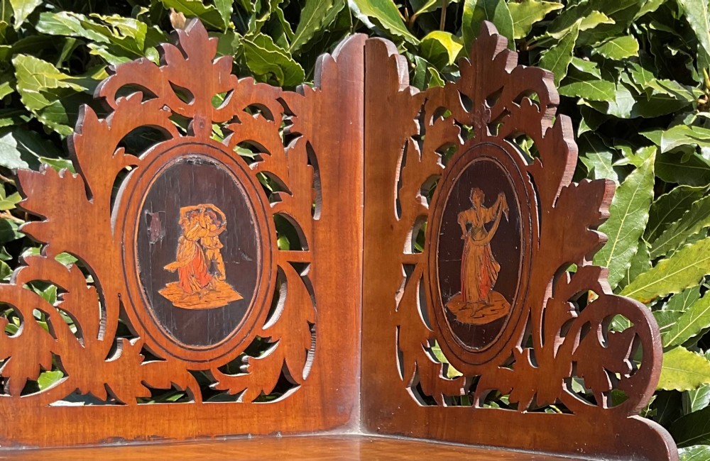 A Victorian three-tiered olive wood corner shelf with pierced fretwork edges and oval inlaid marquetry panels depicting Italian figures. View II