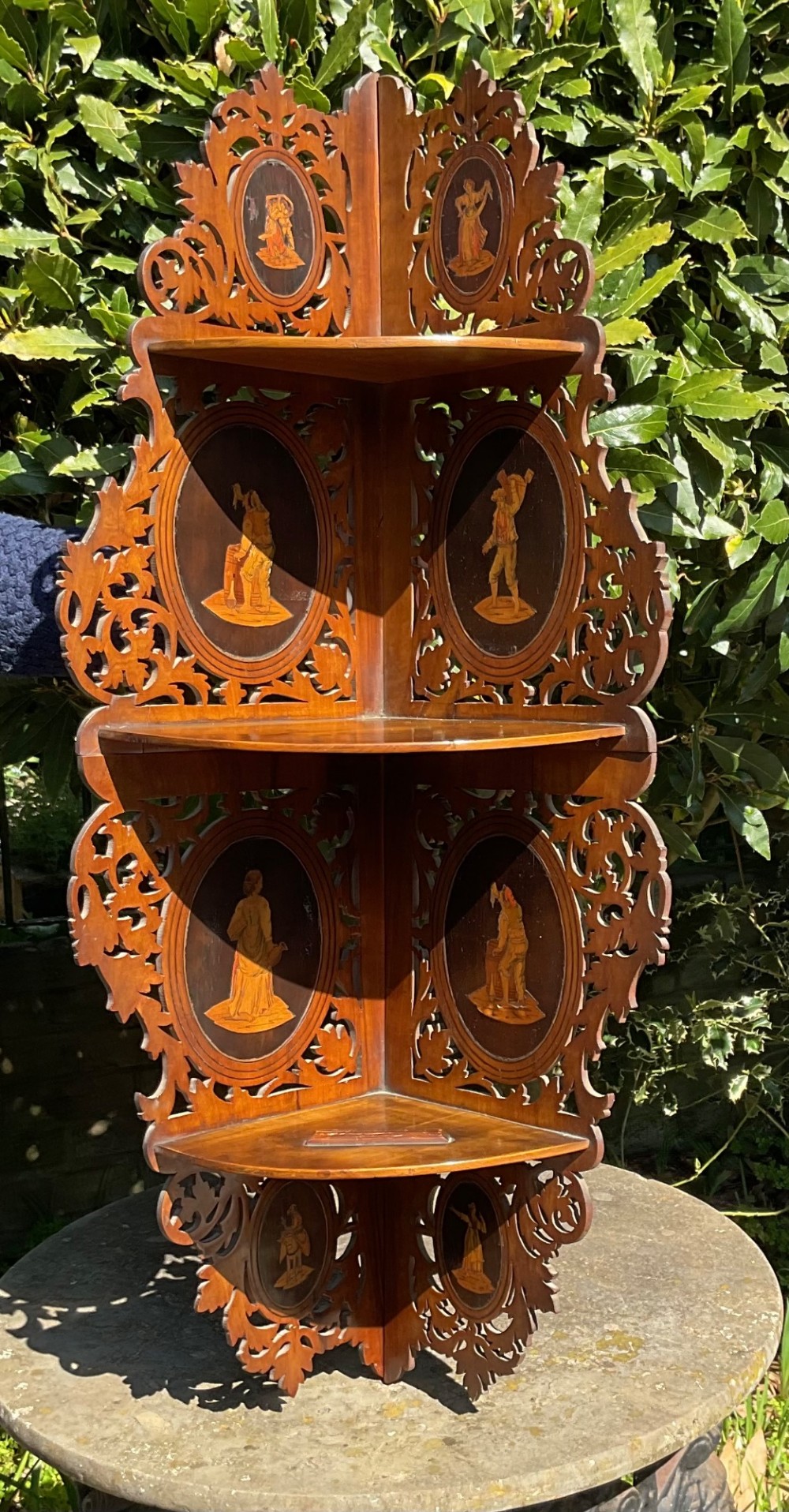 A Victorian three-tiered olive wood corner shelf with pierced fretwork edges and oval inlaid marquetry panels depicting Italian figures. View IX
