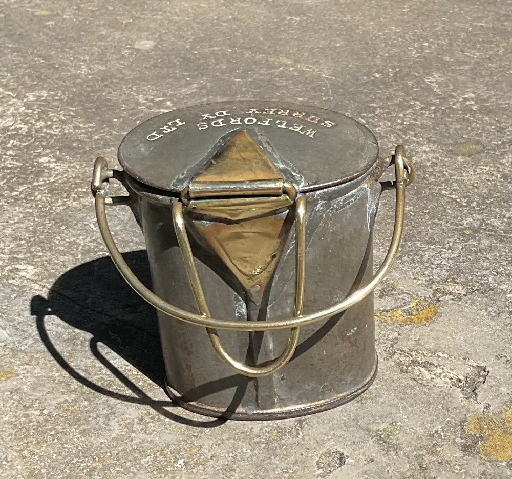 An antique metal dairy cream can featuring a brass swing handle, stamped lid lettering, and a hinged spout cover. View VI