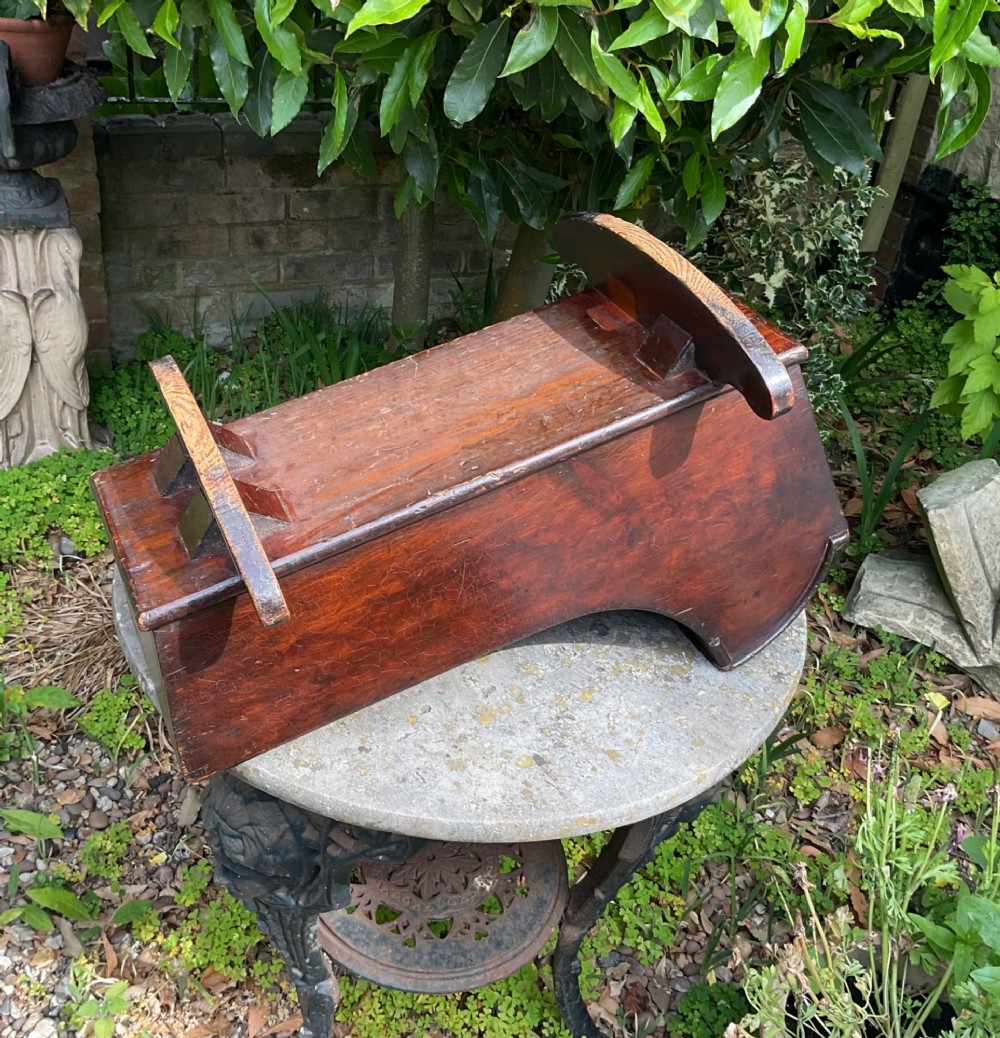 A Georgian pine miniature doll cradle featuring a hooded canopy, scalloped front moulding, and curved wooden rockers in a warm brown finish. View VIII