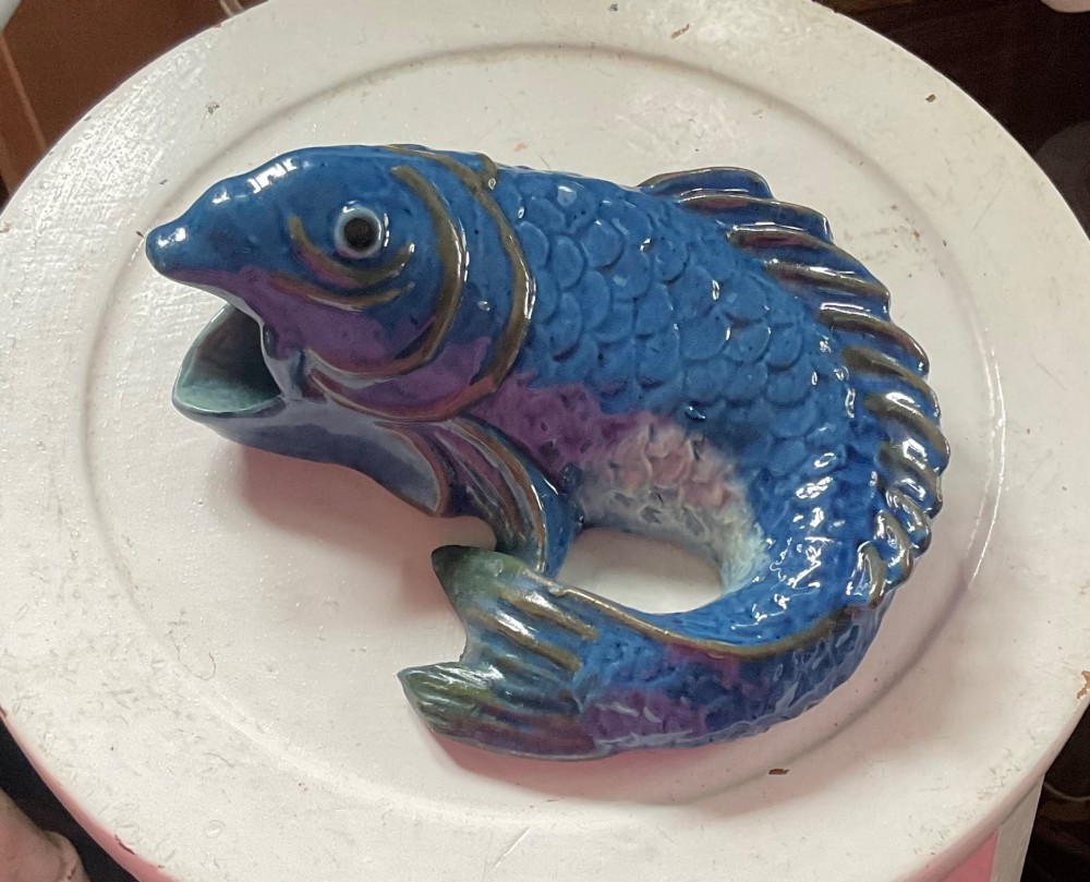 A glazed earthenware wall pocket modelled in the form of a fish with blue scales, green fins, and an open mouth vessel.