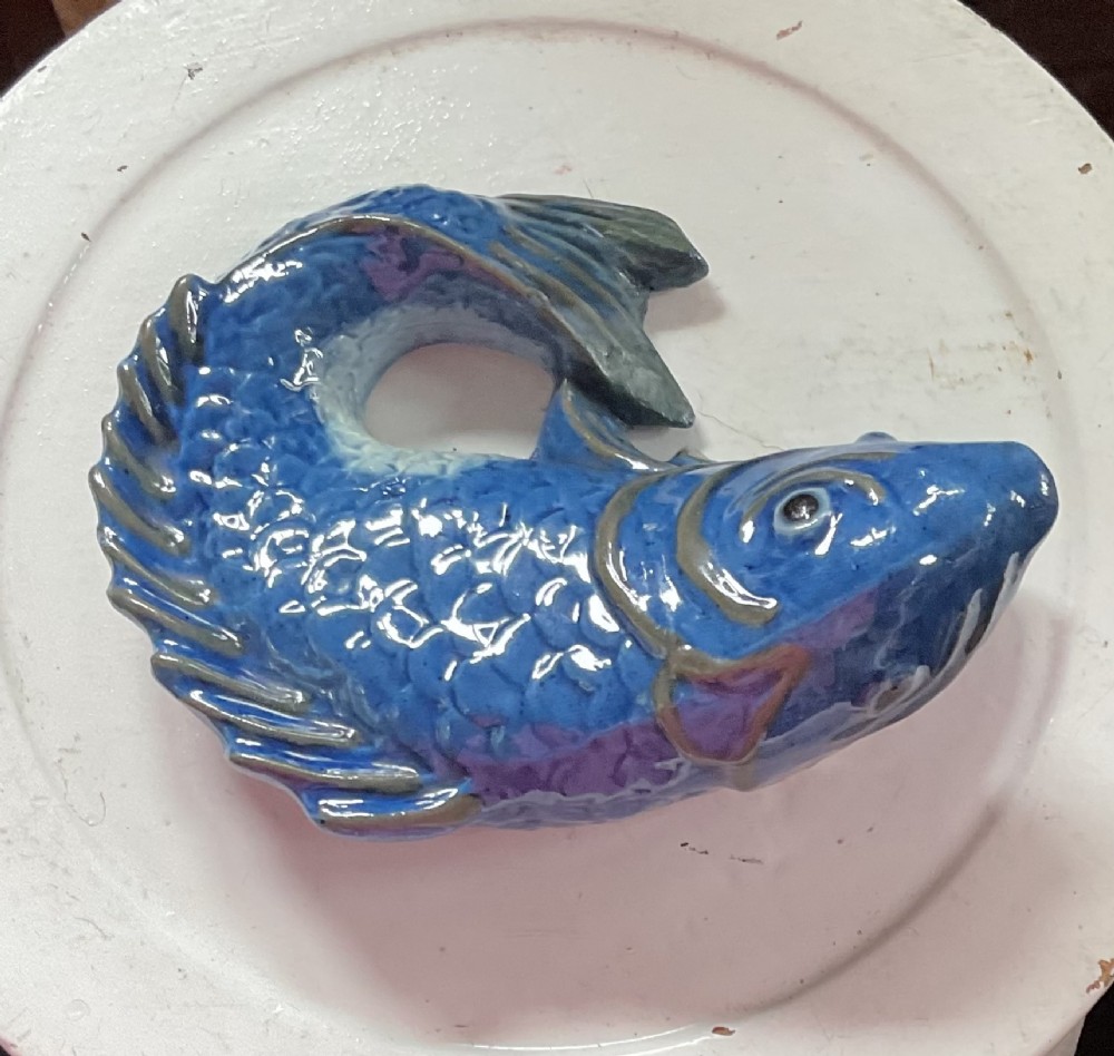 A glazed earthenware wall pocket modelled in the form of a fish with blue scales, green fins, and an open mouth vessel. View III
