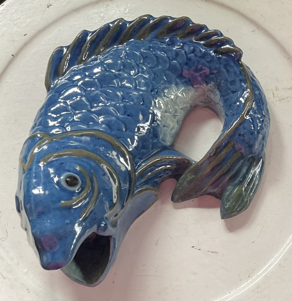 A glazed earthenware wall pocket modelled in the form of a fish with blue scales, green fins, and an open mouth vessel. View IV