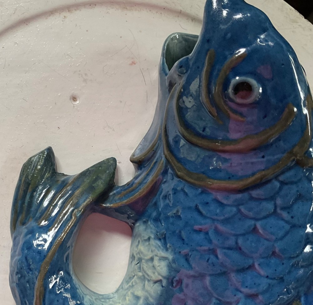 A glazed earthenware wall pocket modelled in the form of a fish with blue scales, green fins, and an open mouth vessel. View VI