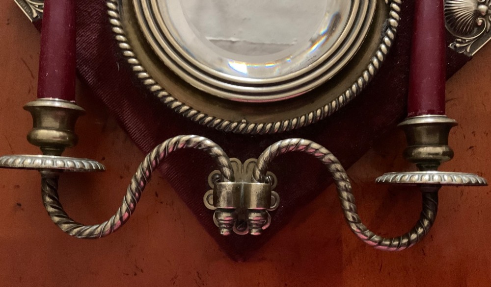A pair of diamond-shaped Victorian girandole mirrors featuring burgundy velvet fabric, brass shell corner mounts, circular mirrors, and twin brass candle branches. View IV