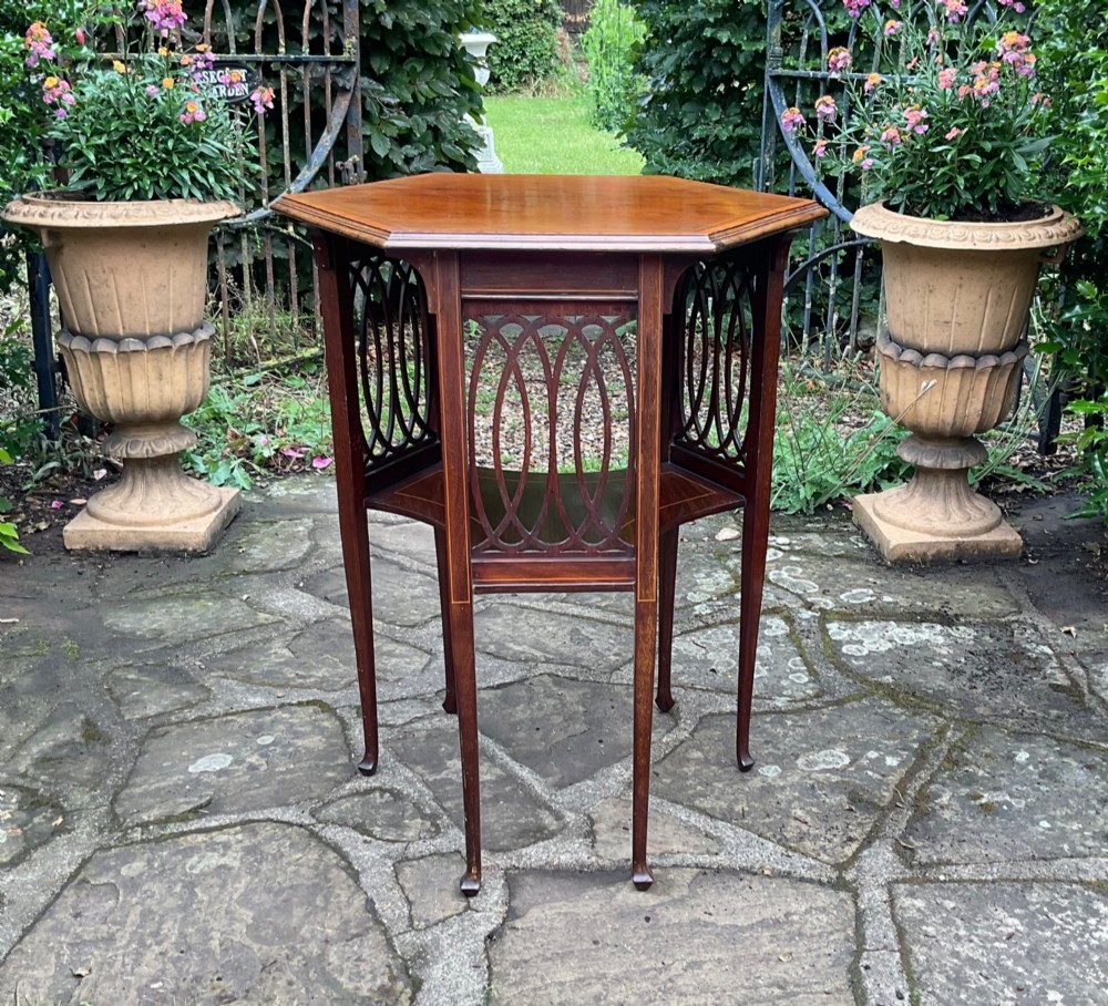 An Edwardian octagonal mahogany lamp table featuring line inlay, a concave lower shelf, and pierced oval fretwork side panels. View II