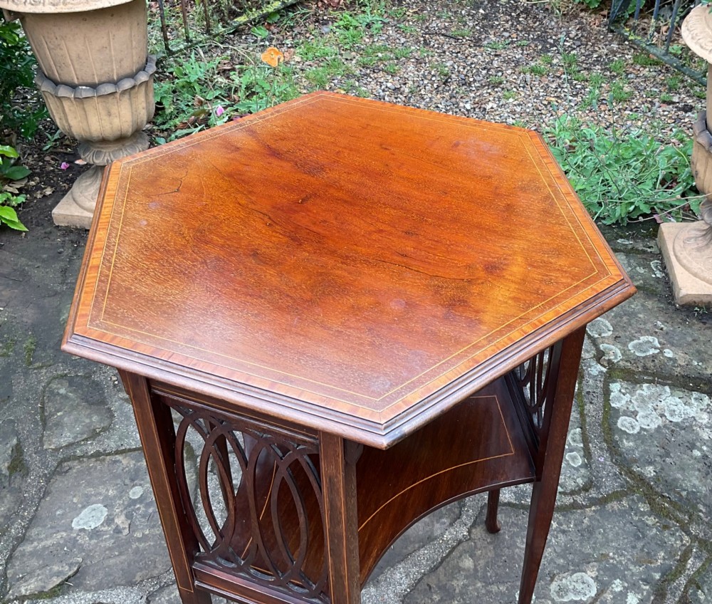 An Edwardian octagonal mahogany lamp table featuring line inlay, a concave lower shelf, and pierced oval fretwork side panels. View III