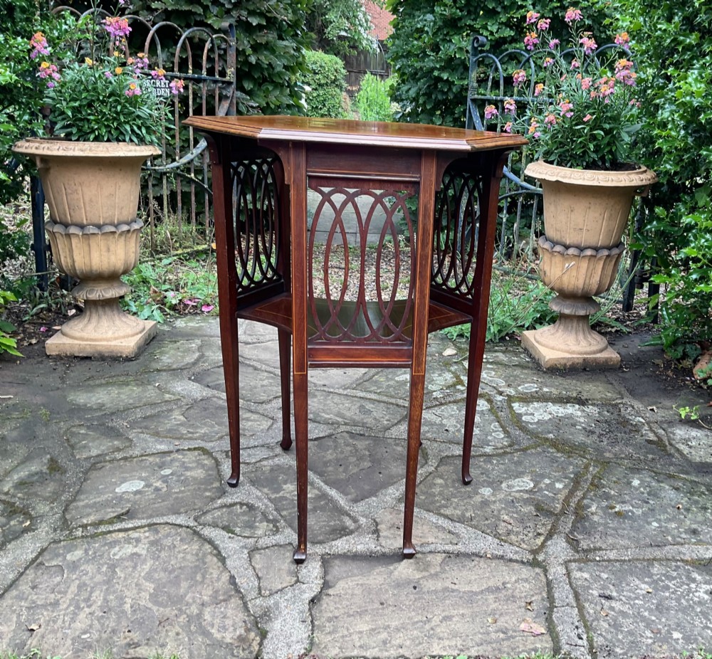 An Edwardian octagonal mahogany lamp table featuring line inlay, a concave lower shelf, and pierced oval fretwork side panels. View IV
