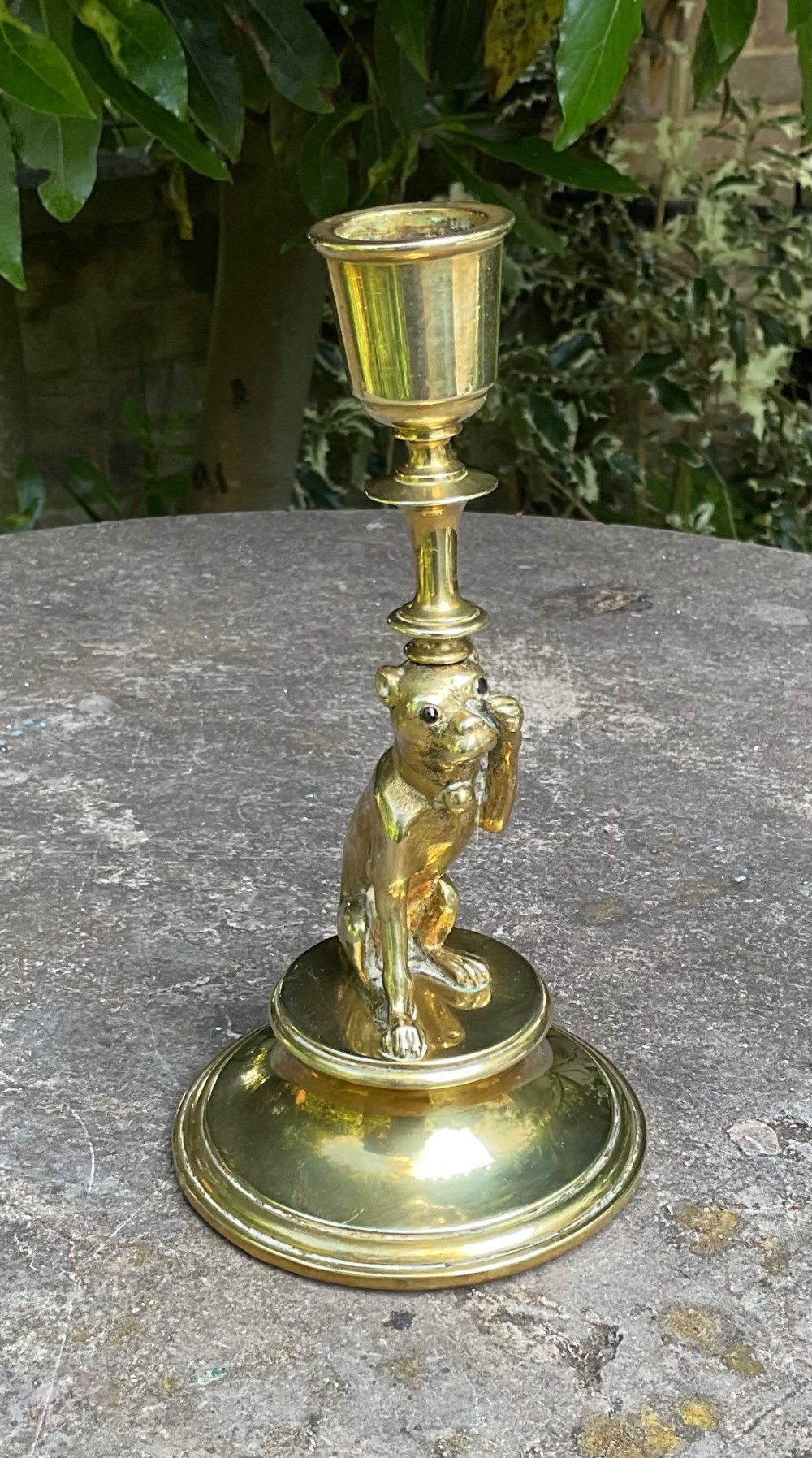 A Victorian cast brass candlestick featuring a sculpted sitting pug dog forming the lower stem above a round stepped base. View IV