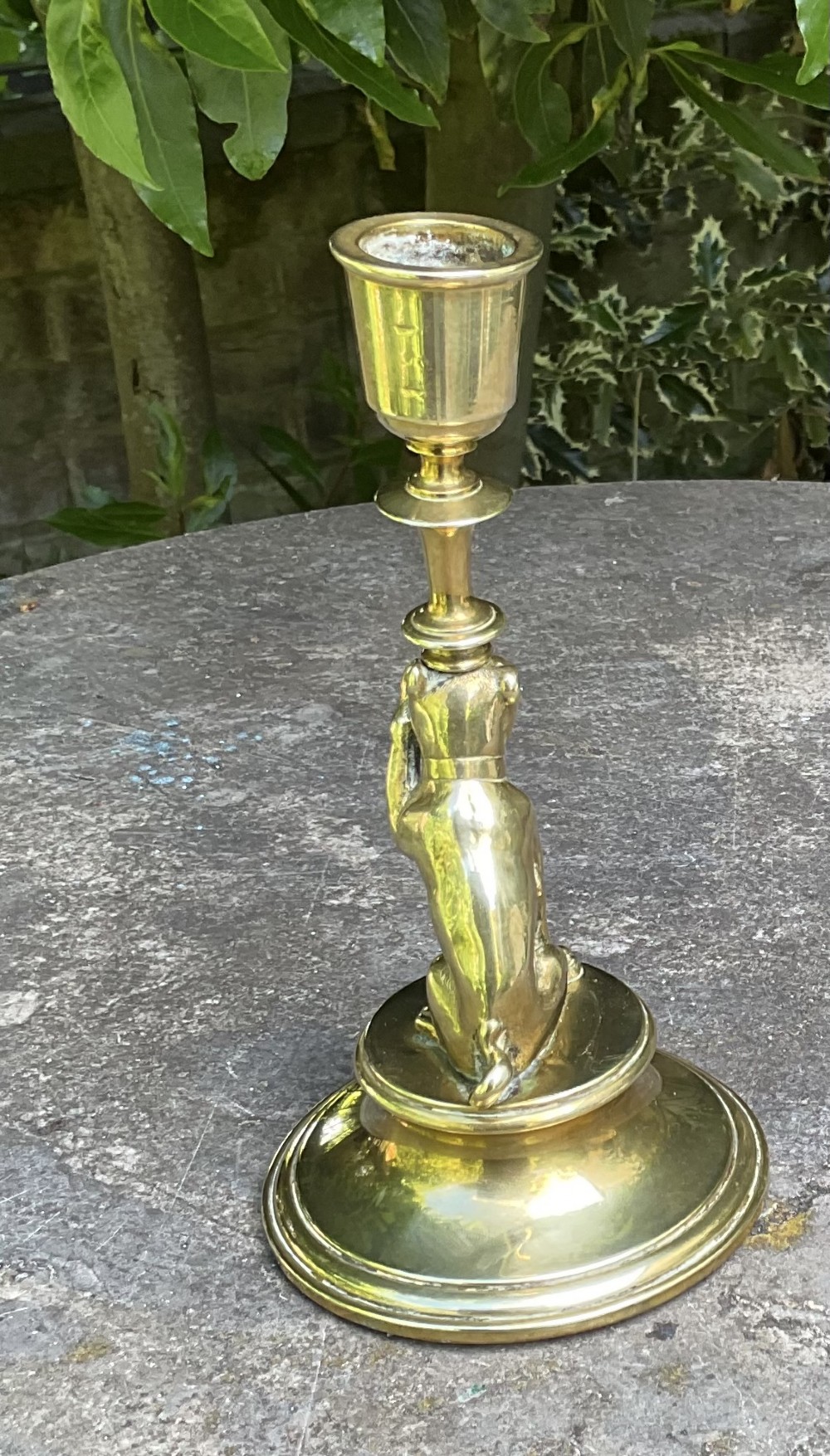 A Victorian cast brass candlestick featuring a sculpted sitting pug dog forming the lower stem above a round stepped base. View VI