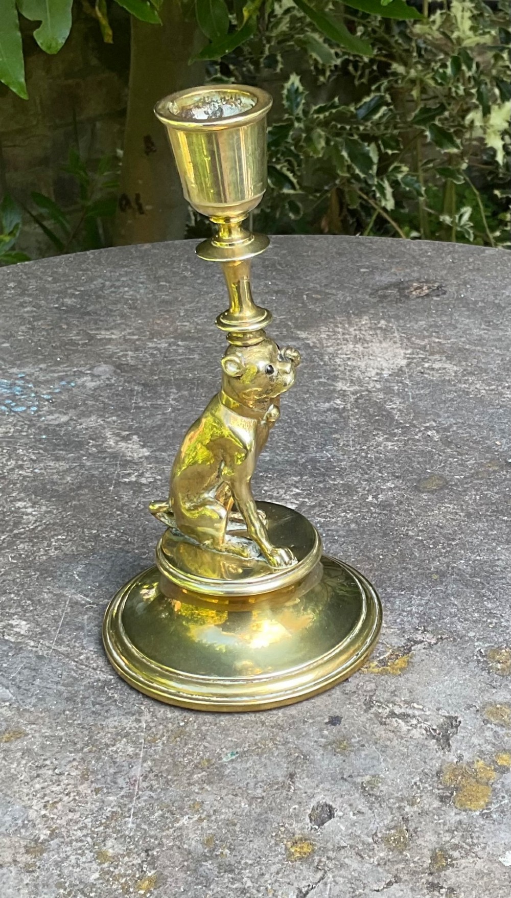 A Victorian cast brass candlestick featuring a sculpted sitting pug dog forming the lower stem above a round stepped base. View VII