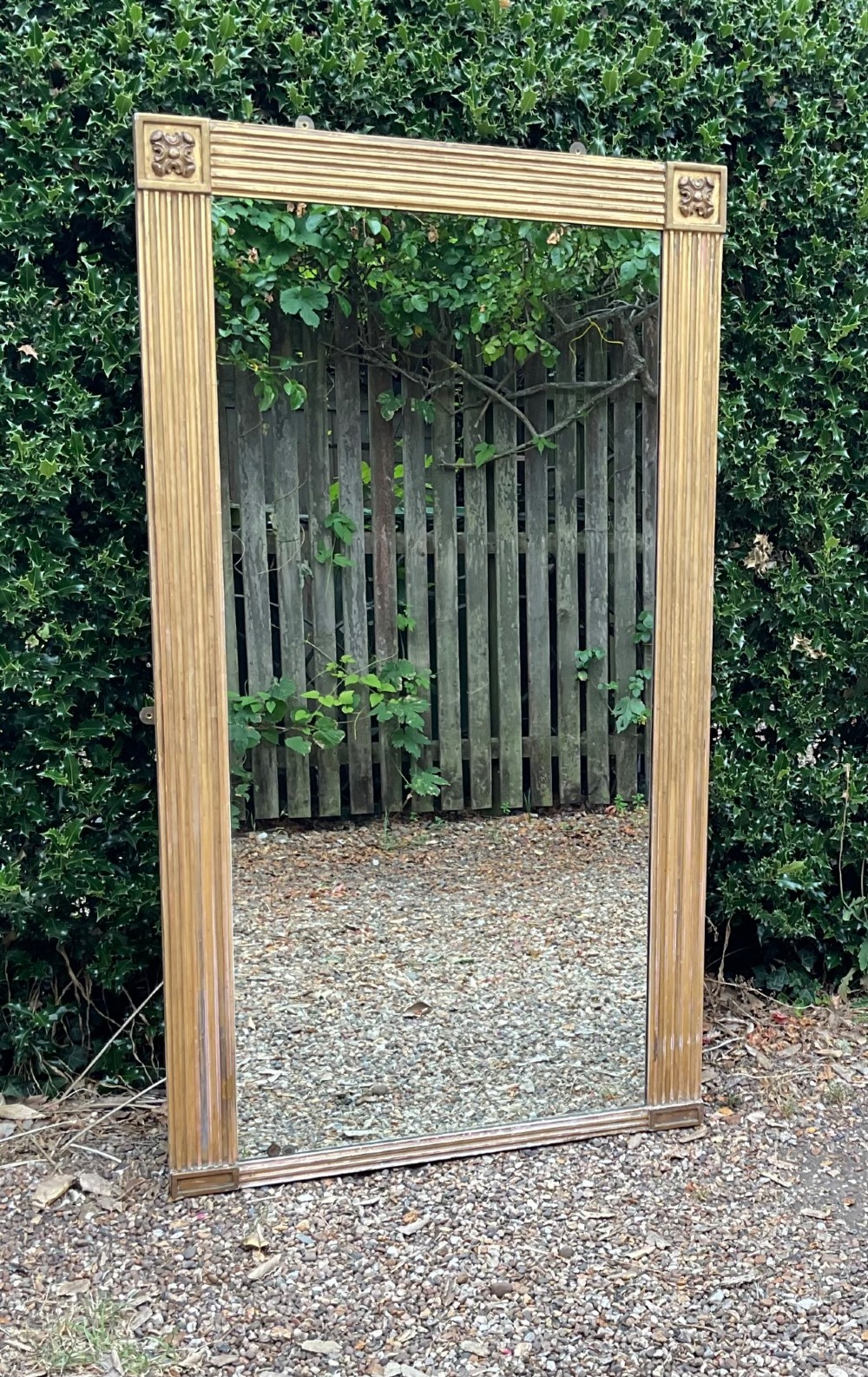 A tall Regency giltwood pier mirror featuring a fluted frame with carved corner rosettes.
