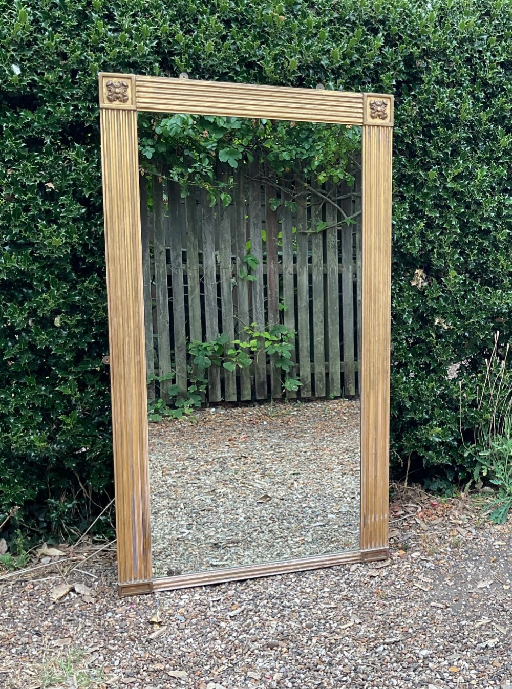 A tall Regency giltwood pier mirror featuring a fluted frame with carved corner rosettes. View IX