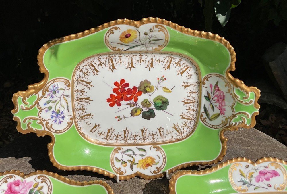 A set of four Regency period Chamberlains Worcester porcelain serving dishes featuring bright apple green borders, gilt scrollwork, and individual hand-painted central botanical flowers. View II