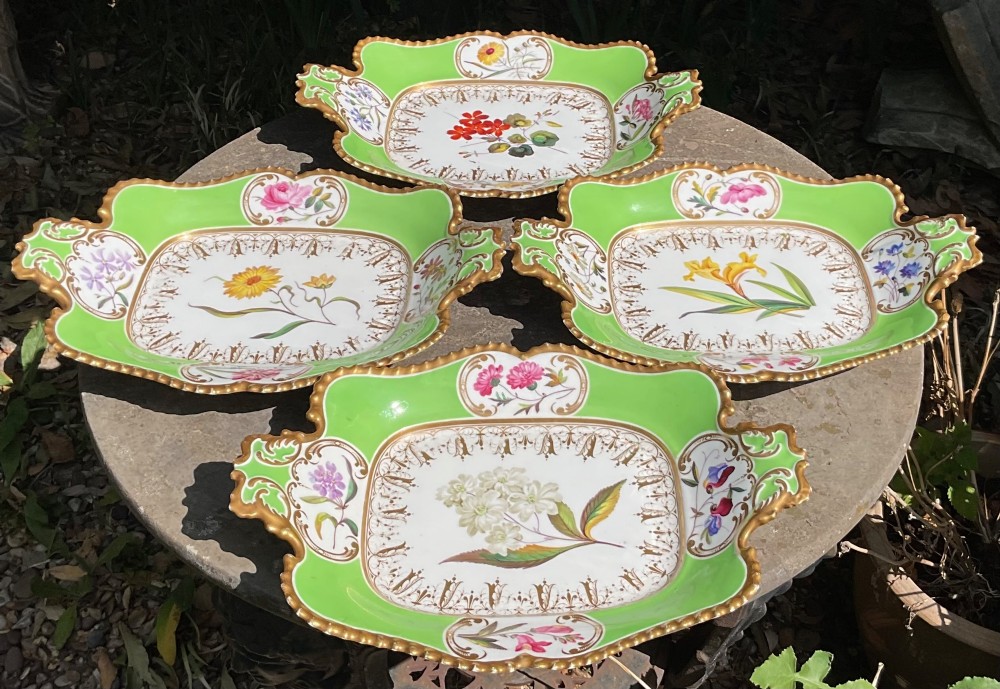 A set of four Regency period Chamberlains Worcester porcelain serving dishes featuring bright apple green borders, gilt scrollwork, and individual hand-painted central botanical flowers. View VII