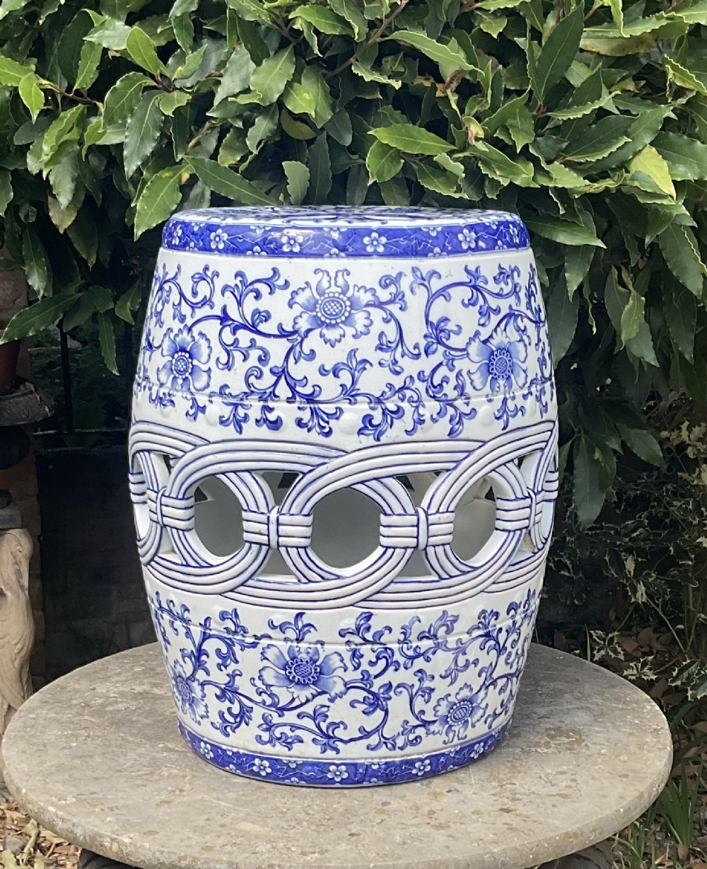 A Victorian barrel-shaped ceramic garden seat decorated with blue floral patterns on a white background and featuring a central band of intertwined openwork rings.