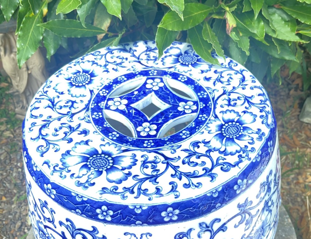 A Victorian barrel-shaped ceramic garden seat decorated with blue floral patterns on a white background and featuring a central band of intertwined openwork rings. View II