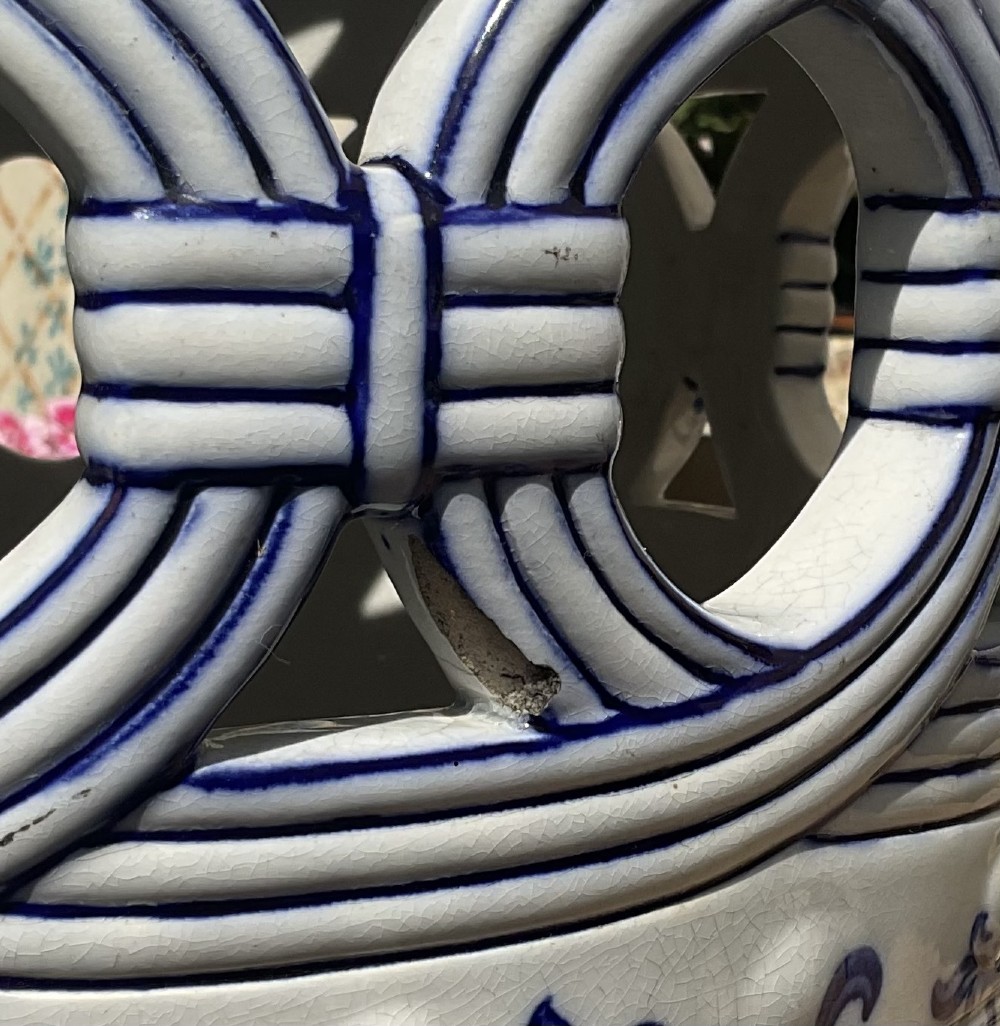 A Victorian barrel-shaped ceramic garden seat decorated with blue floral patterns on a white background and featuring a central band of intertwined openwork rings. View V