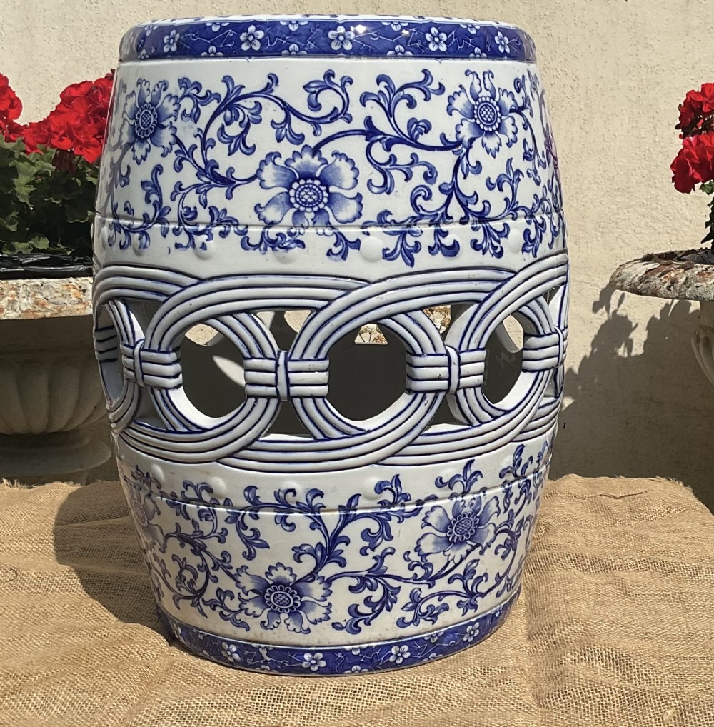 A Victorian barrel-shaped ceramic garden seat decorated with blue floral patterns on a white background and featuring a central band of intertwined openwork rings. View VI