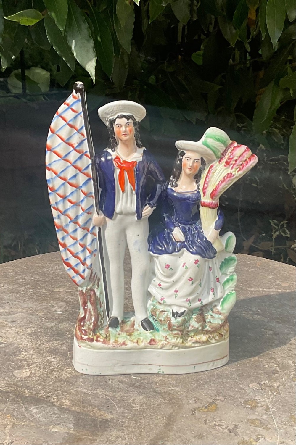 A Victorian Staffordshire earthenware flatback figure group depicting a sailor holding a flag alongside a female figure holding a sheaf of corn. View VI