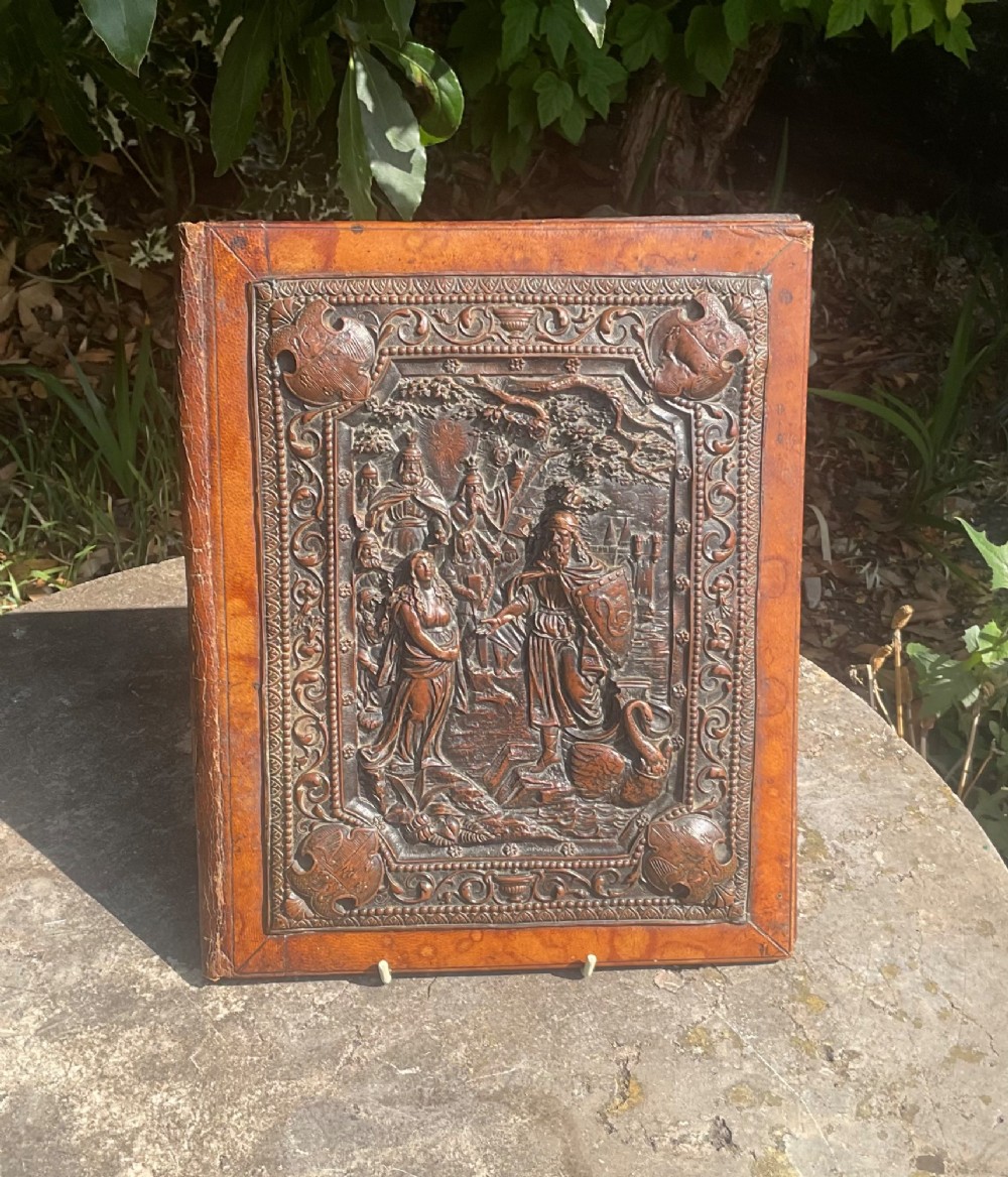 An antique brown leather desk blotter featuring a central embossed copper relief panel depicting a scene from Wagners opera Lohengrin with a knight and swan.