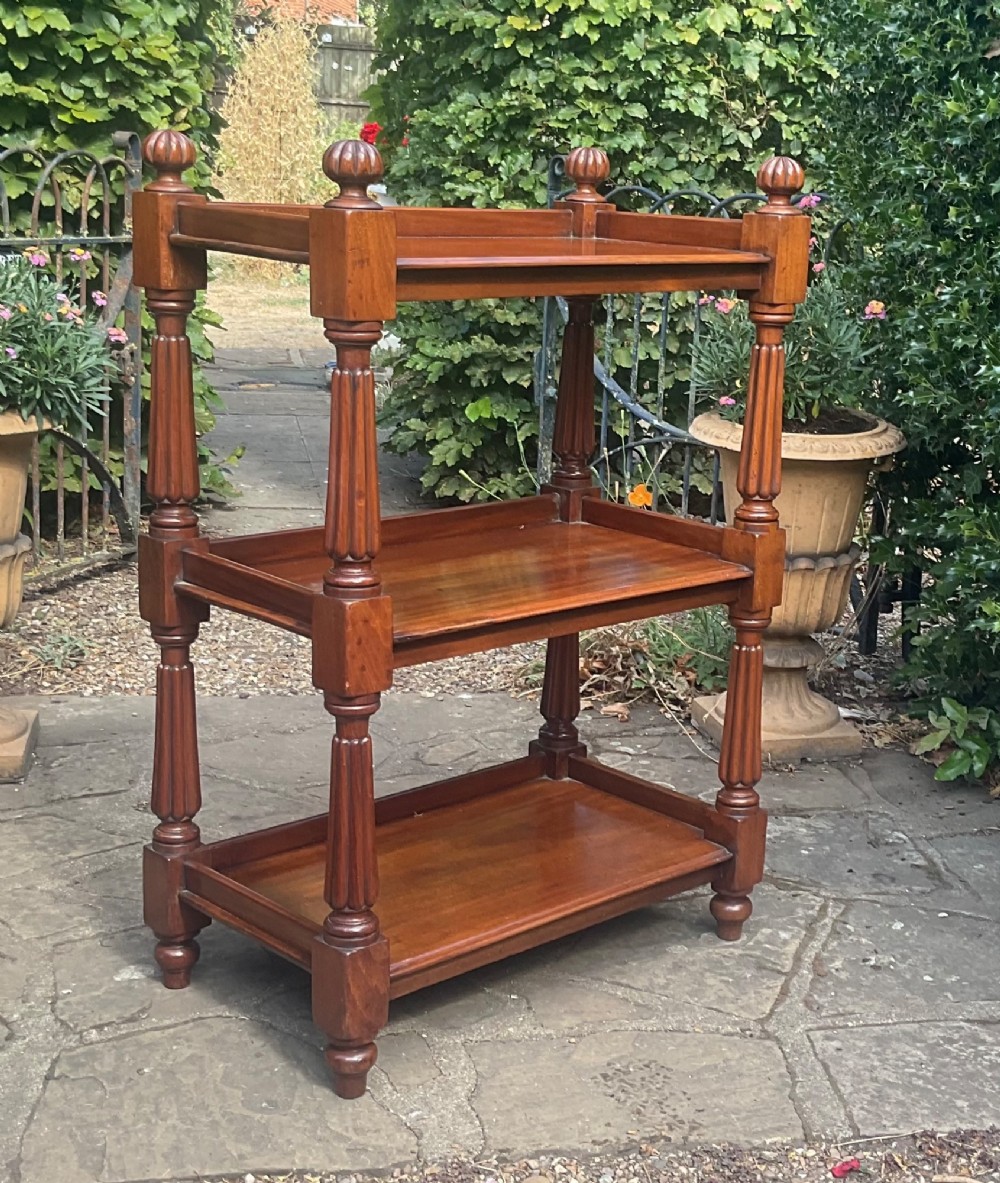 A Victorian mahogany three-tier etagere featuring reeded vertical supports, turned finials, and gallery rimmed shelves.
