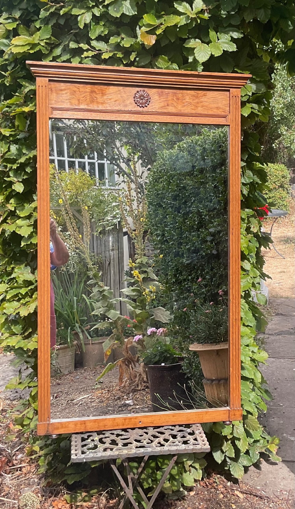A rectangular Edwardian blonde oak mirror featuring a moulded cornice top, central carved rosette motif, fluted side pilasters, and a clear glass plate.