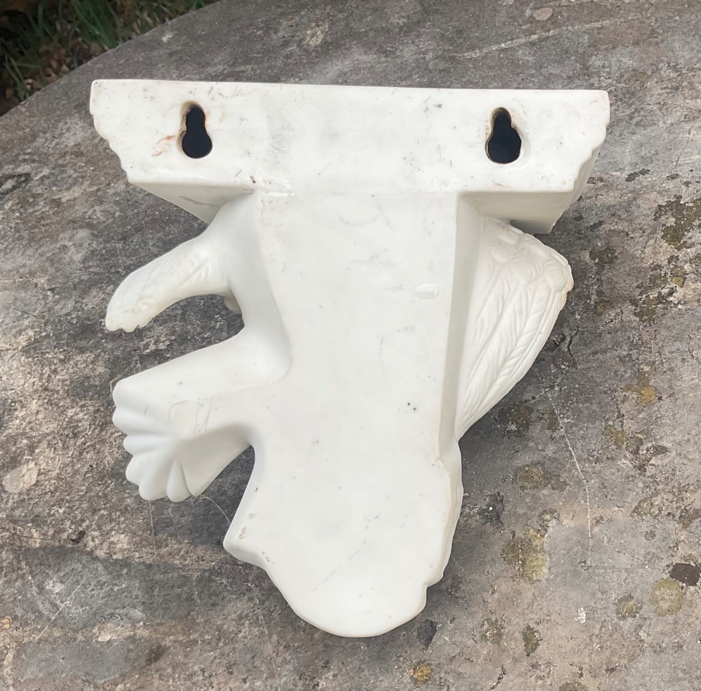 A Victorian off-white Parian porcelain wall bracket featuring a sculpted eagle with outstretched wings perched beneath a stepped shelf ledge. View V