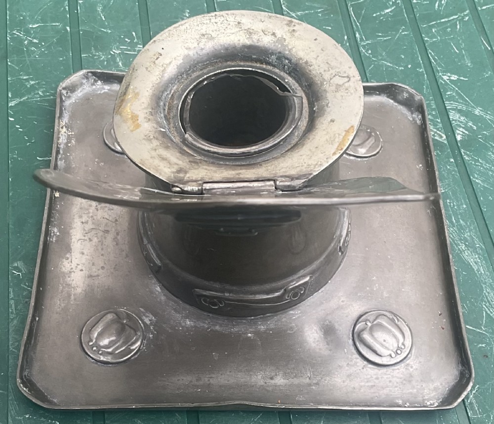 An Arts and Crafts Tudric pewter inkwell featuring a square base tray with raised relief motifs and a central cylindrical body topped with a square lid. View VII