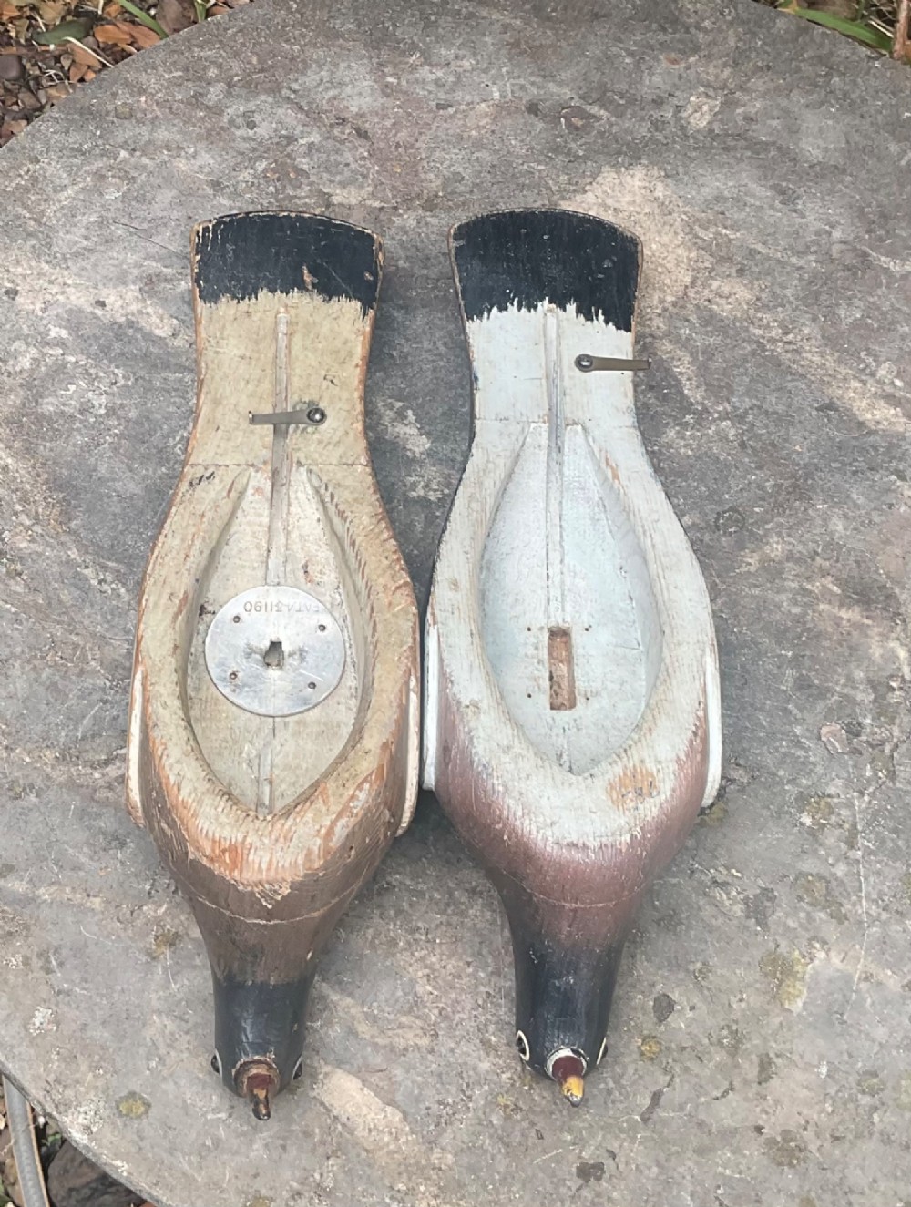 A pair of hand-carved, painted wooden wood pigeon decoys with weathered grey, black, and white plumage. View III