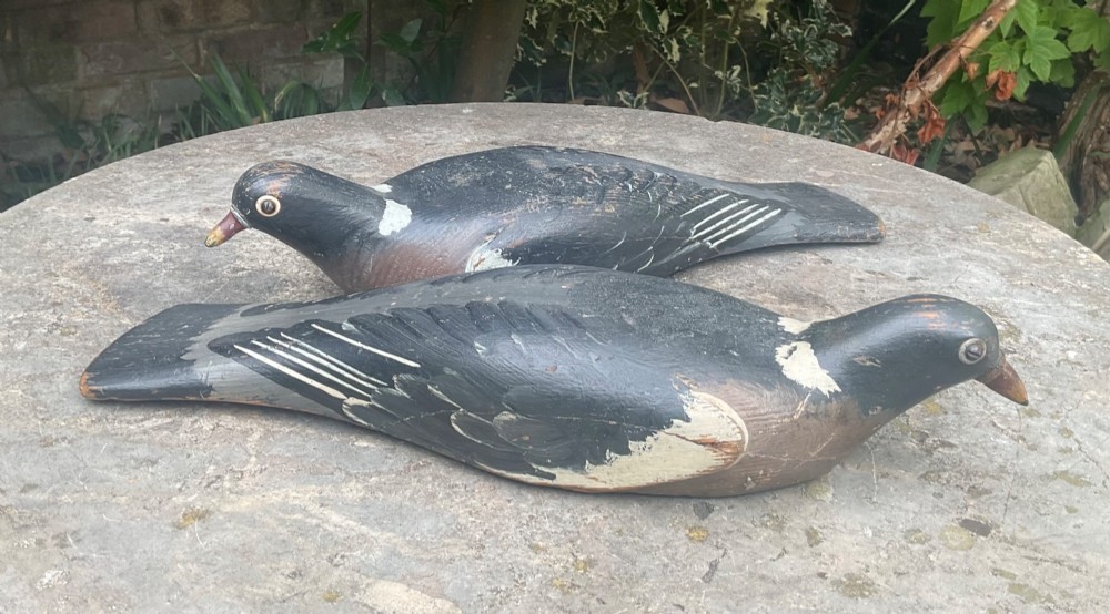 A pair of hand-carved, painted wooden wood pigeon decoys with weathered grey, black, and white plumage. View VI