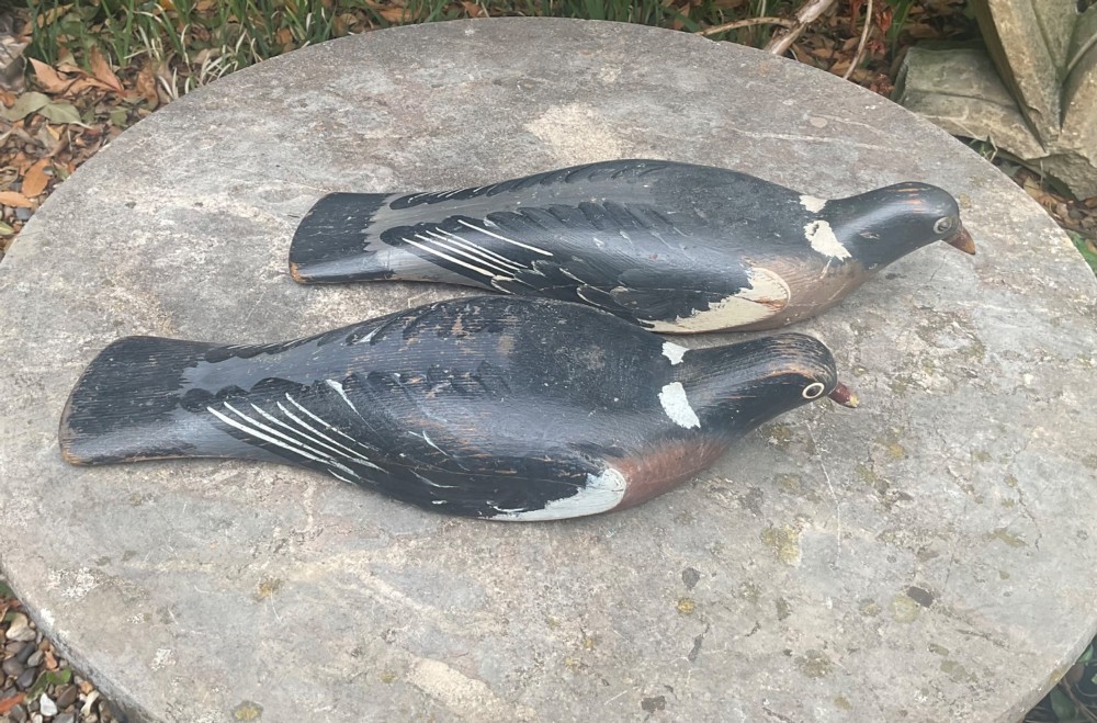 A pair of hand-carved, painted wooden wood pigeon decoys with weathered grey, black, and white plumage. View VII