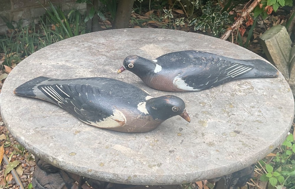 A pair of hand-carved, painted wooden wood pigeon decoys with weathered grey, black, and white plumage. View VIII