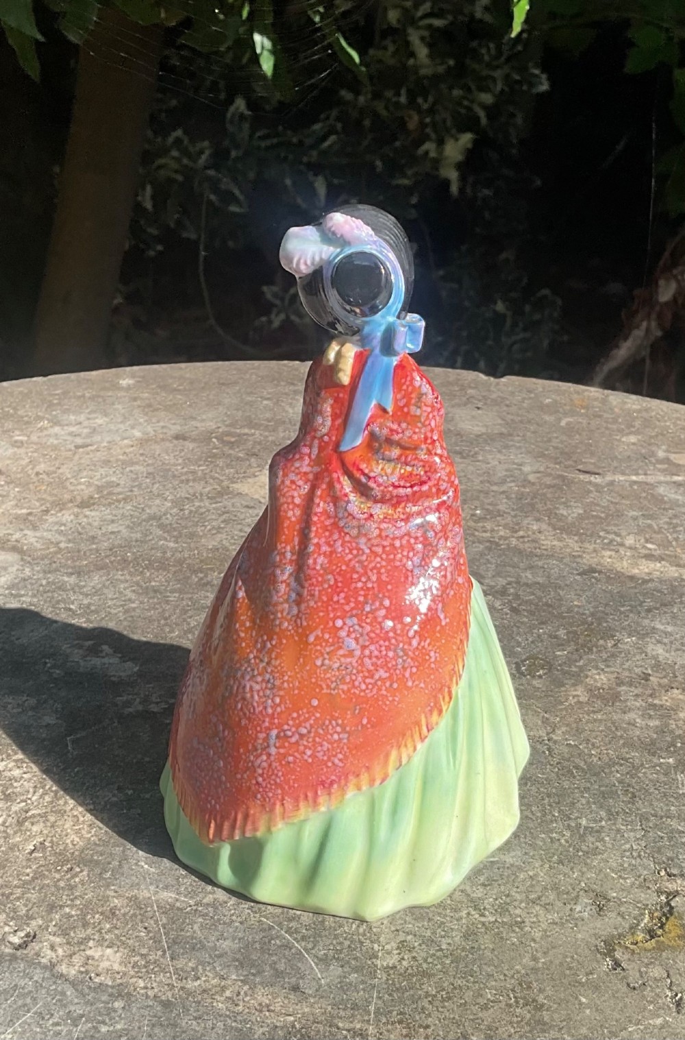 A Royal Doulton fine bone china figurine depicting a woman in a green gown and bonnet holding a parasol and draped in a patterned red shawl. View III